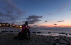person sitting on rock near water