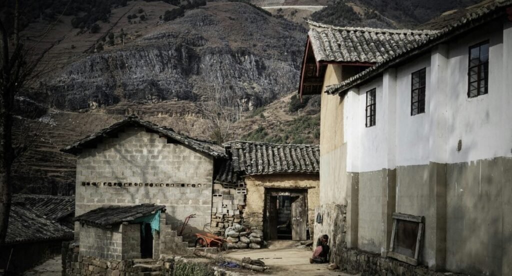 A picturesque village located near a mountain cliff, surrounded by lush greenery and natural beauty