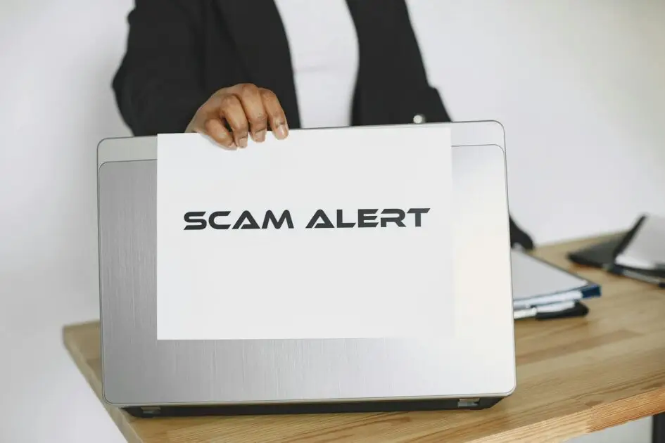 SIM Card Scam_man holding a sheet of paper on the laptop