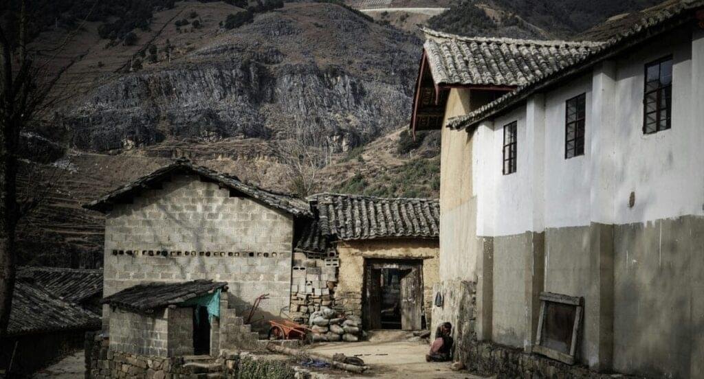 A picturesque village located near a mountain cliff, surrounded by lush greenery and natural beauty