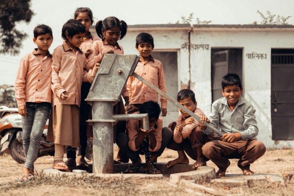 ग्रामीण भारत का विकास - children standing next to manual water pump