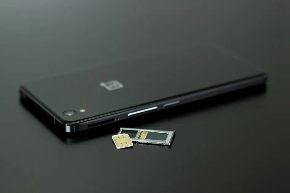 SIM Swap फ्रॉड 2025: black smartphone on black table top